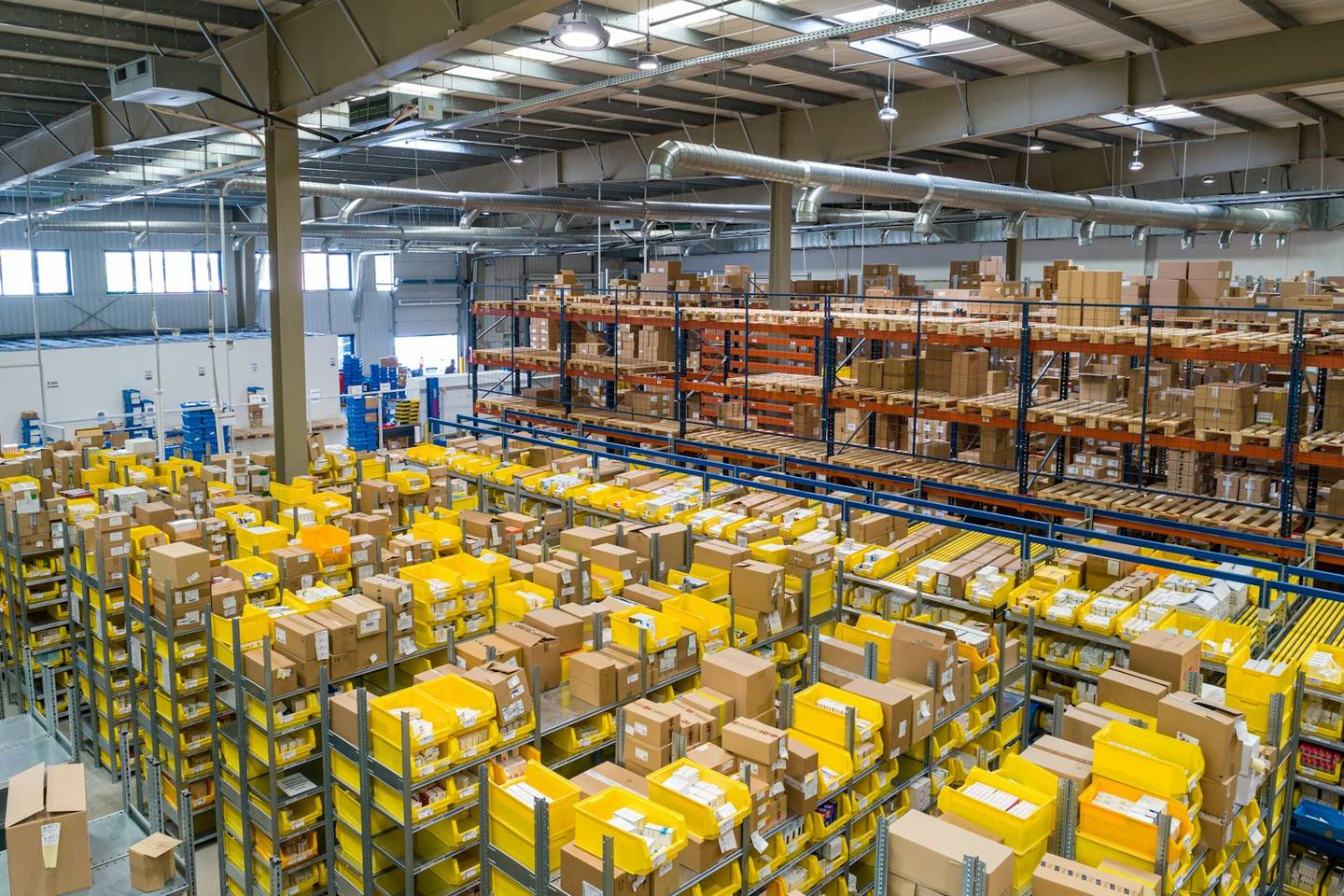Distributiecentrum met stellingen, kartonnen dozen en gele bakken